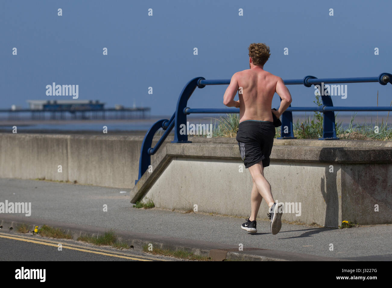 Rear view of man running at Southport, Merseyside, UK.  UK Weather. 2nd May, 2017. Short sleeve weather 16C and warming as joggers enjoy the warming temperatures on the resort seafront. Credit; MediaWorldImages/ AlamyLiveNews. Stock Photo