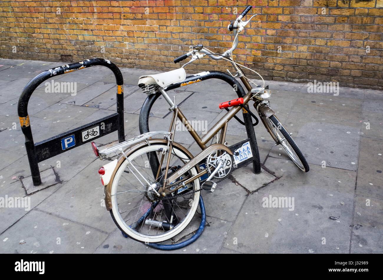 A vintage Raleigh Shopper bike locked to a post in Brick Lane in London's East End. Stock Photo