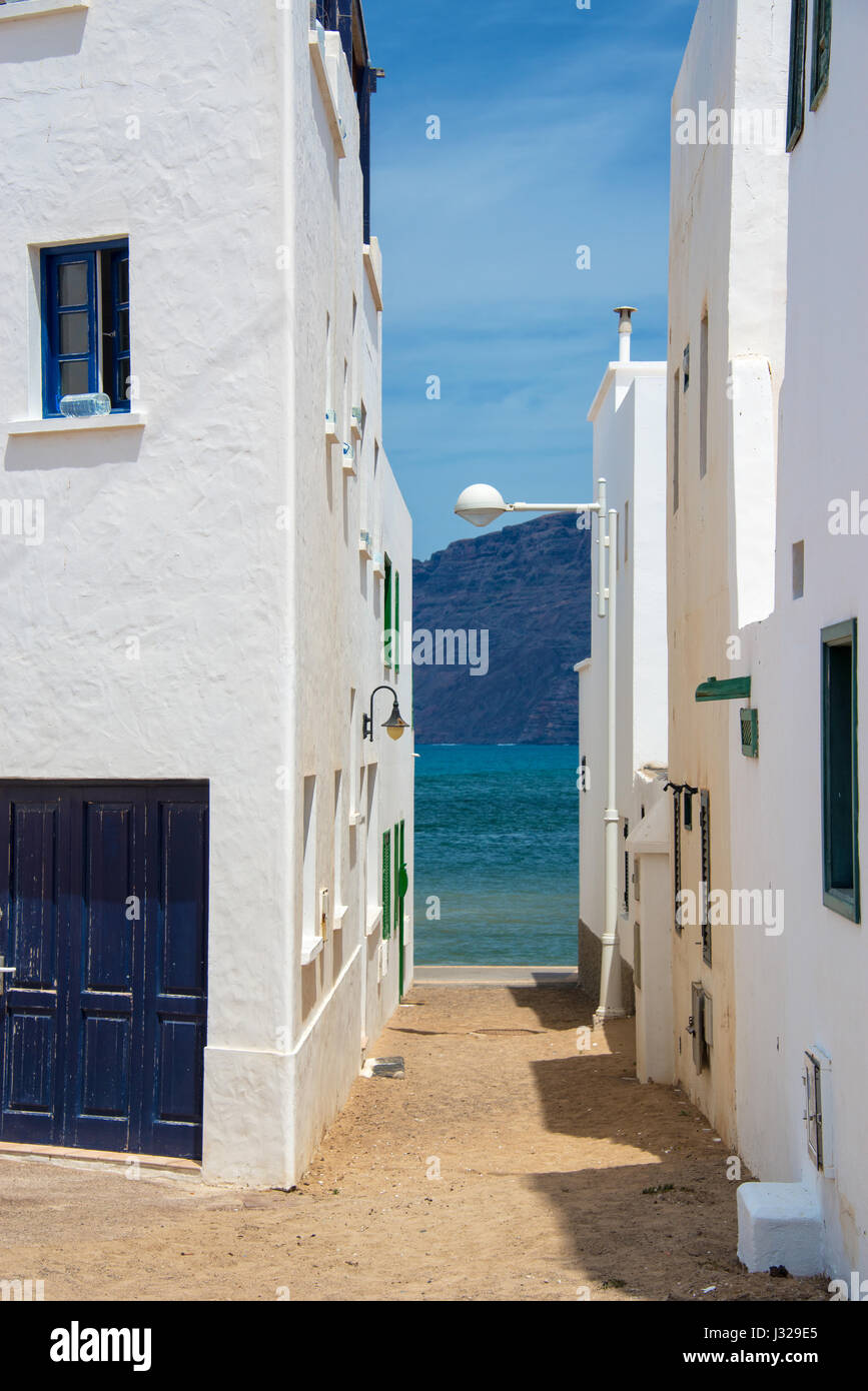 Small street in a white village of Lanzarote, view on the ocean, Canary islands, Spain Stock Photo