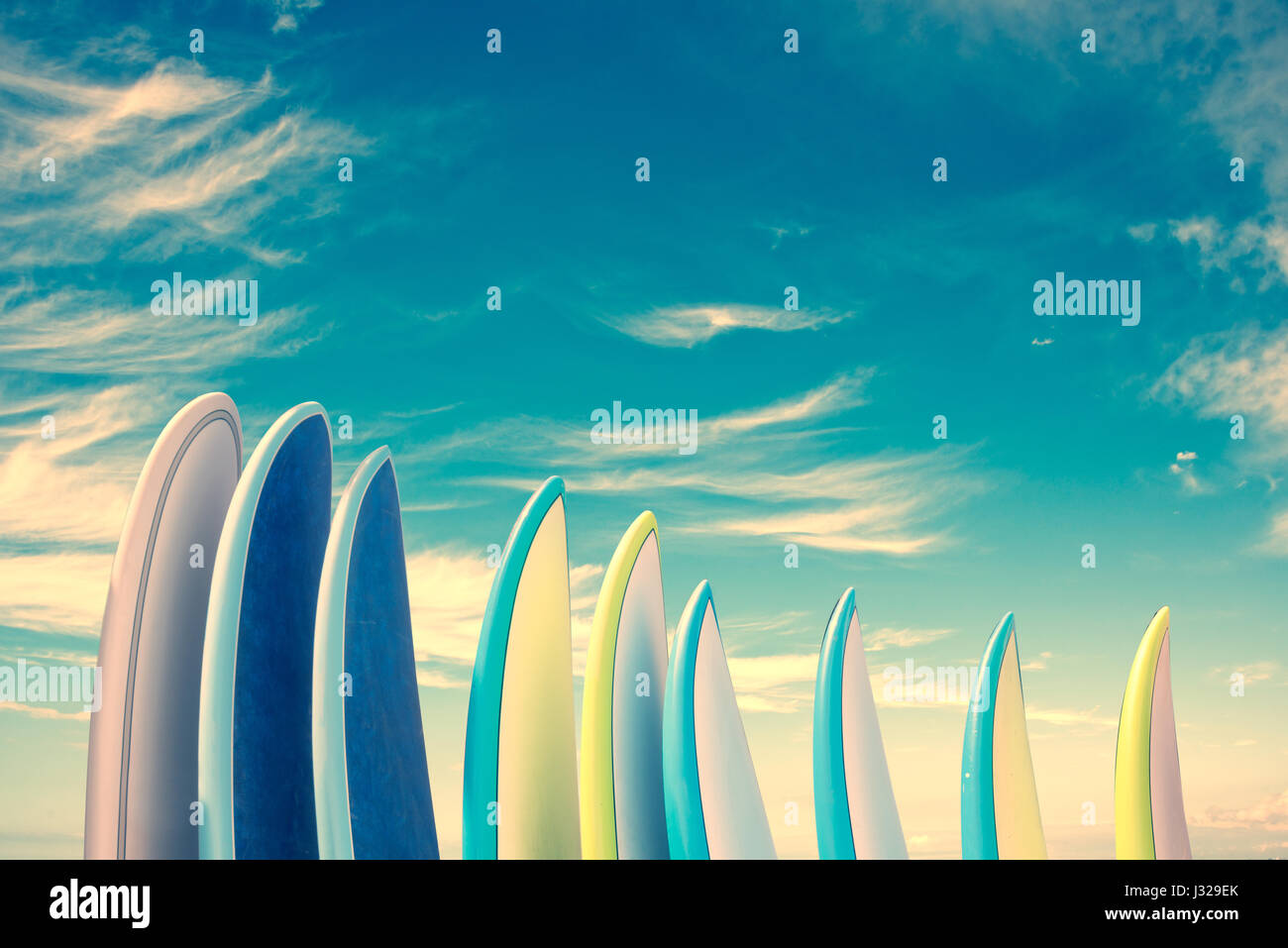 Stack of colorful surfboards on blue sky background with copy space, retro vintage filter Stock Photo