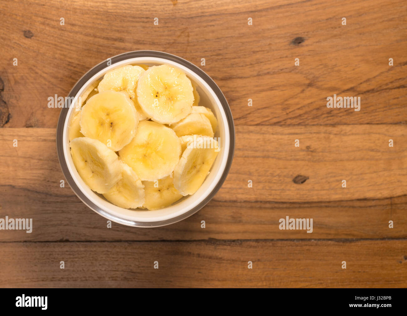 Banana slices freshly washed and sitting on old wood table surface Stock Photo