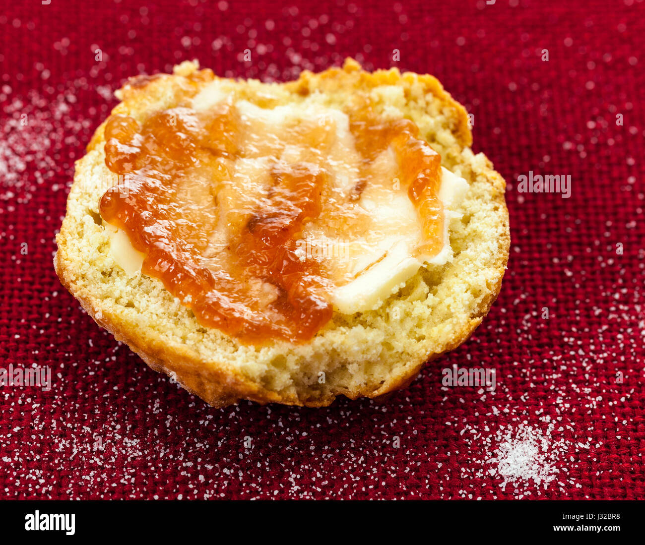 Home made scone with strawberry jam on a red tablecloth Stock Photo