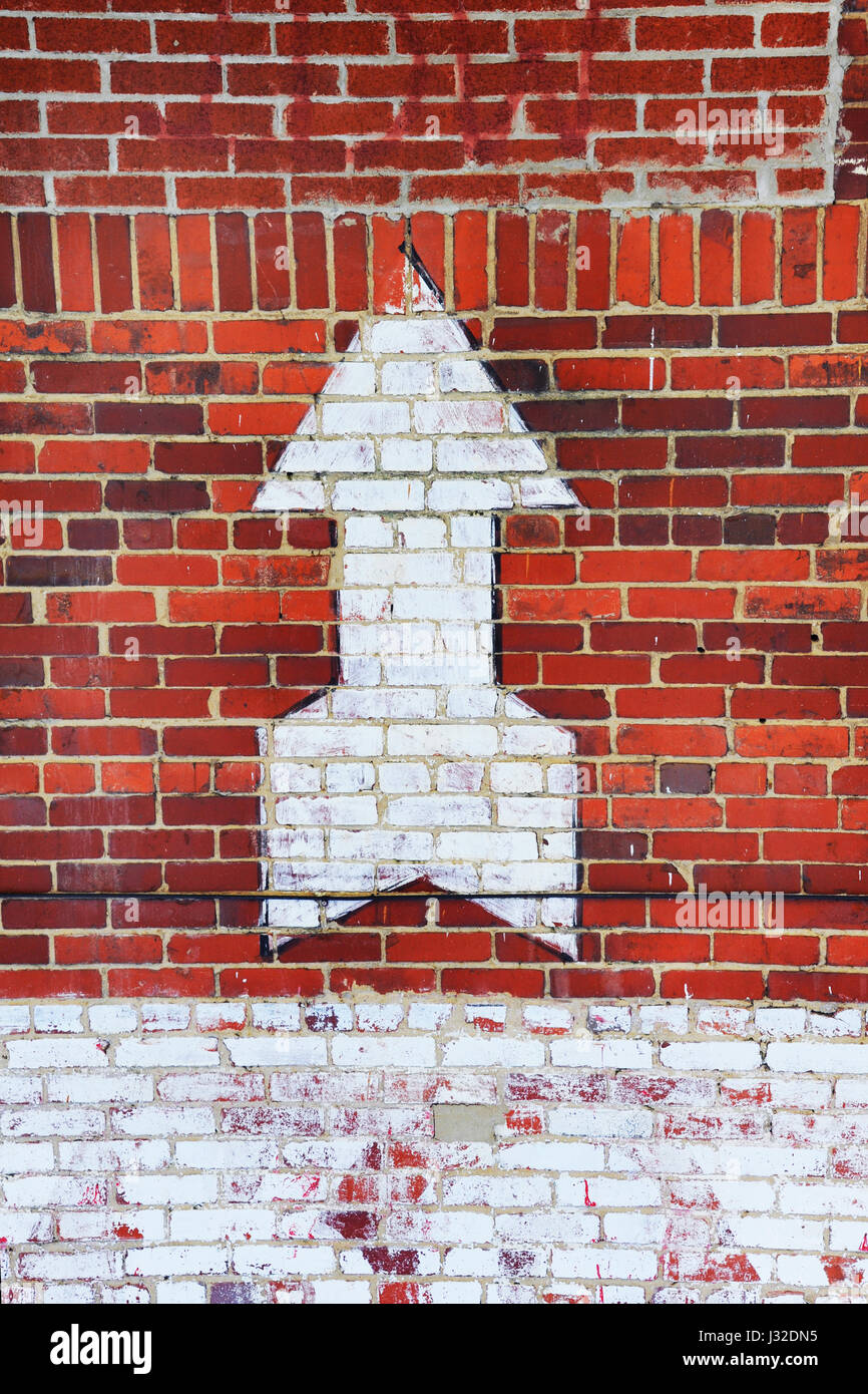 Painted white arrow points upward as it sits on the exterior of old brick building in downtown Kingsport, Tennessee. Stock Photo