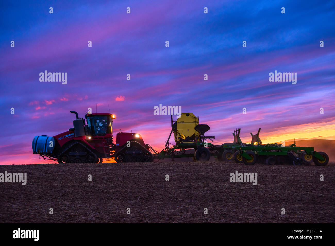 Case quadtrac tractor with fertilizer tanks pulling an air drill planting spring wheat at sunset in the Palouse region of Washington Stock Photo