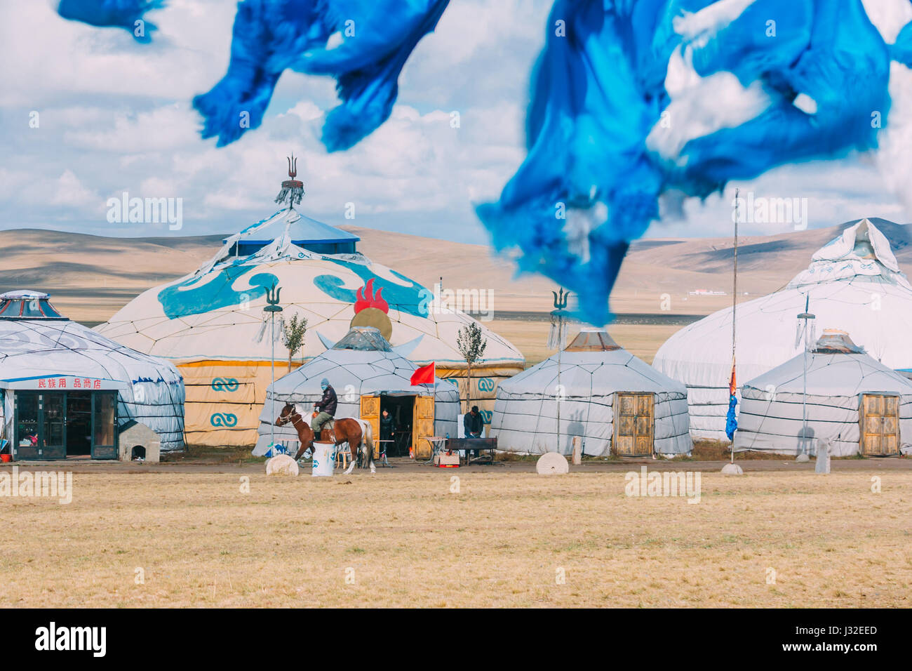 20140924 Inner mogolia,China a mogolian local ride a horse in front of group of yurts in mongolia ,in grassland with blue sky Stock Photo