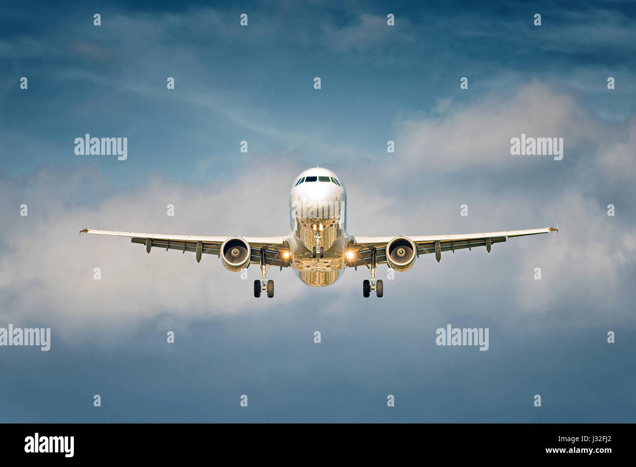 Front view of a big jet plane taking off on blue cloudy sky background Stock Photo