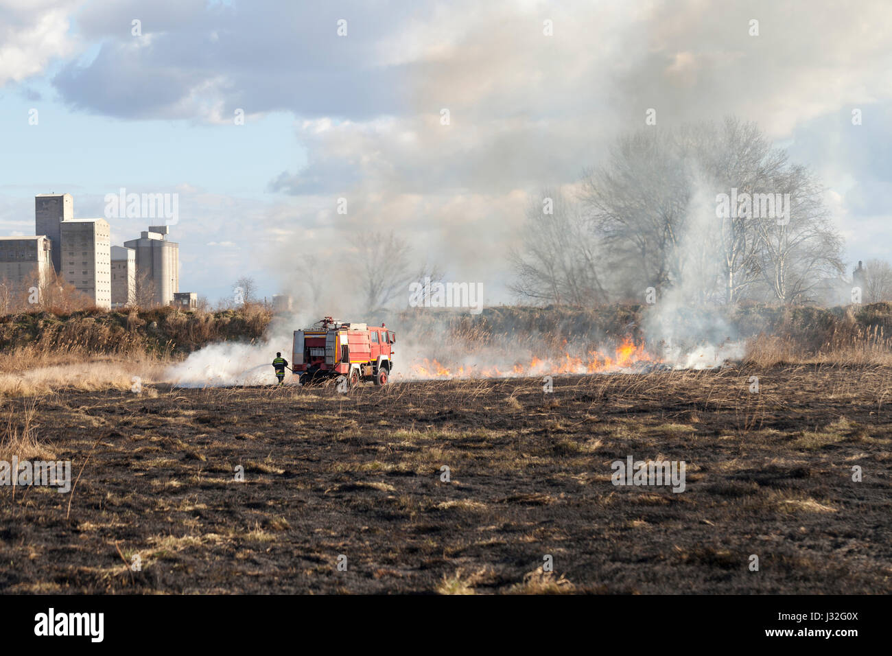 Firefighting on the field. Firefighter with a truck and a fire hose