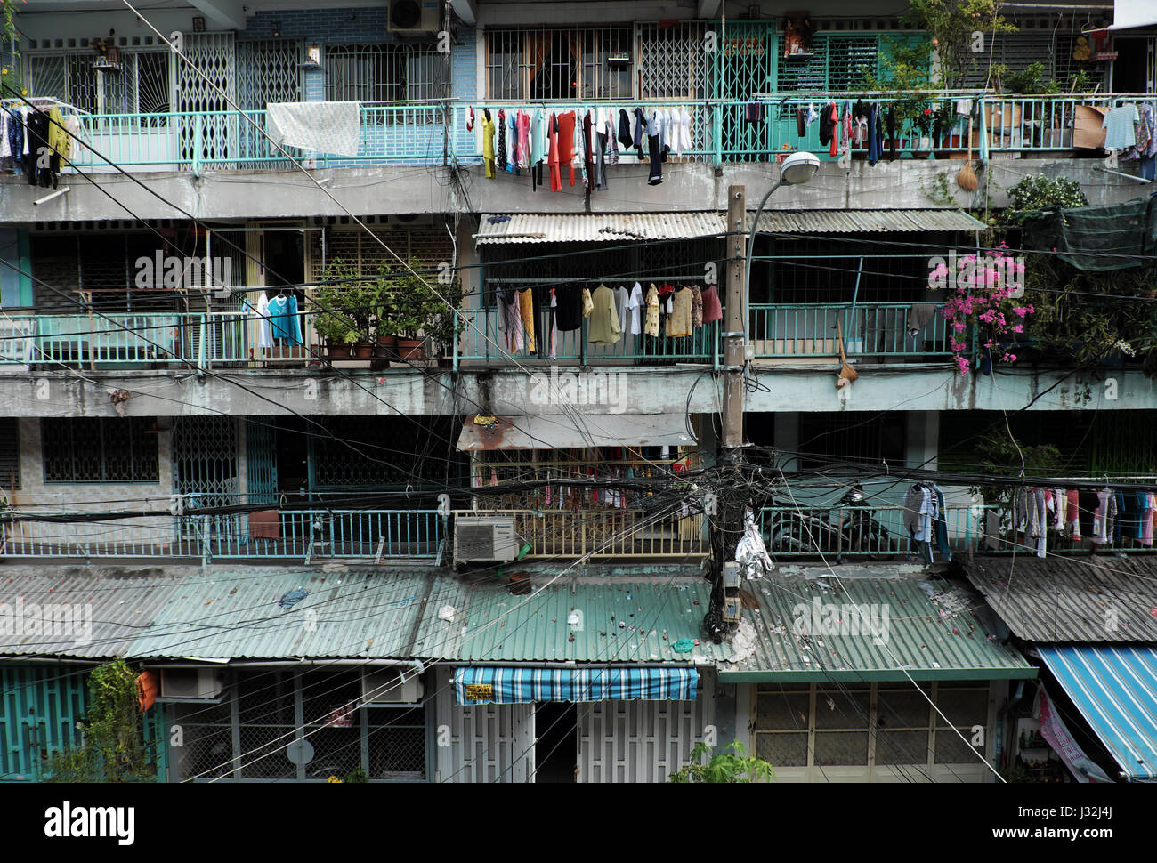 Ho Chi Minh city, Viet Nam, Facade building of old apartment with electric wire interlaced, clothesline make clutter front of house, Vietnam Stock Photo