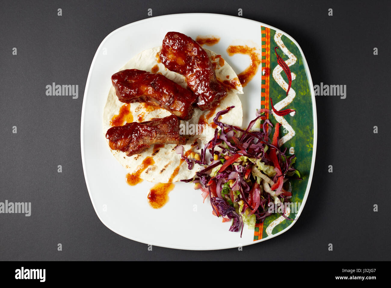 Pork ribs in Mexican style. Mexican food. Mexican cuisine. Studio shot on dark or black background. Stock Photo