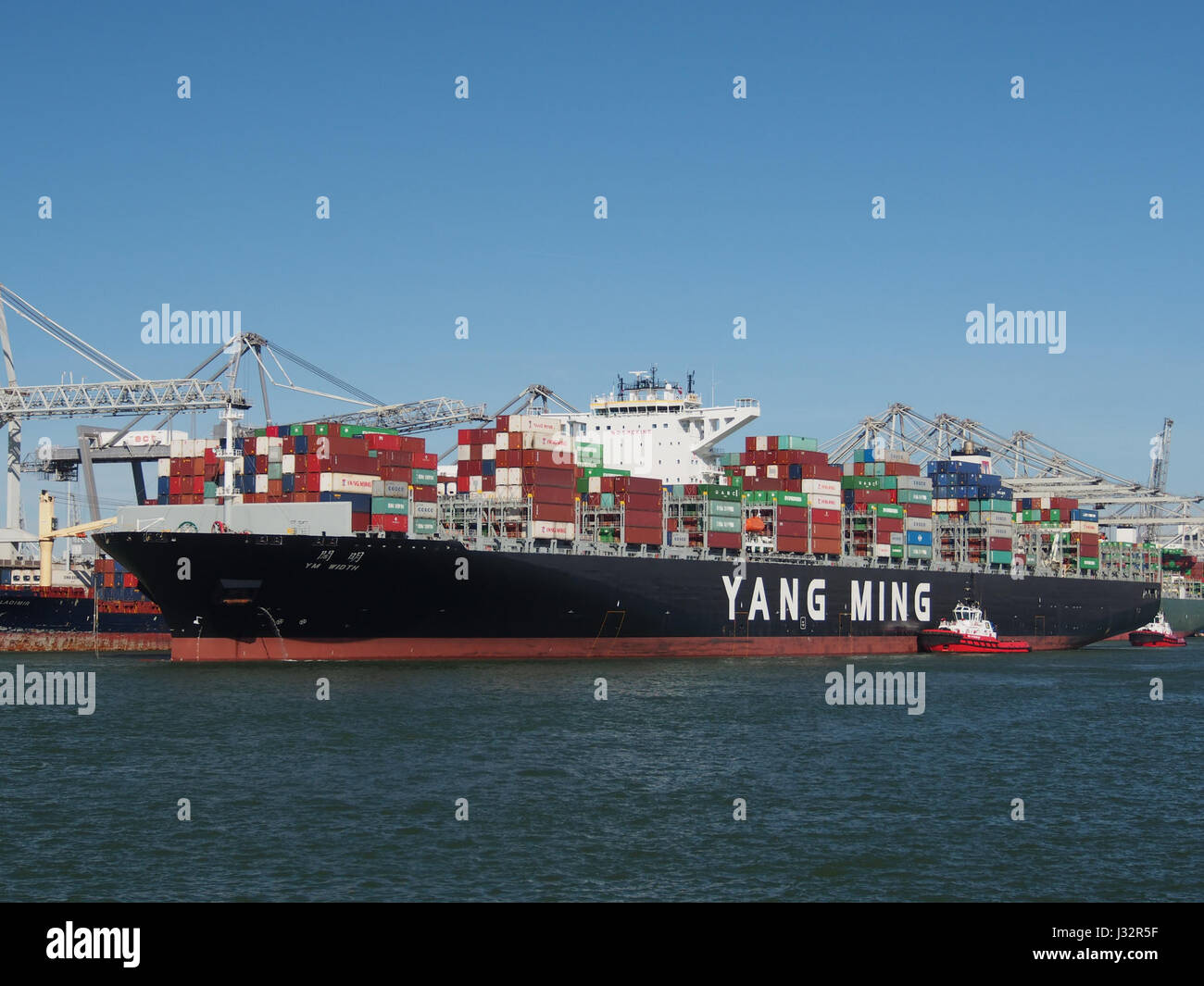 A ship named YM Width, with IMO number 9708447, is seen arriving at the Port of Rotterdam in 2016. This large container vessel is part of the global shipping industry. Stock Photo