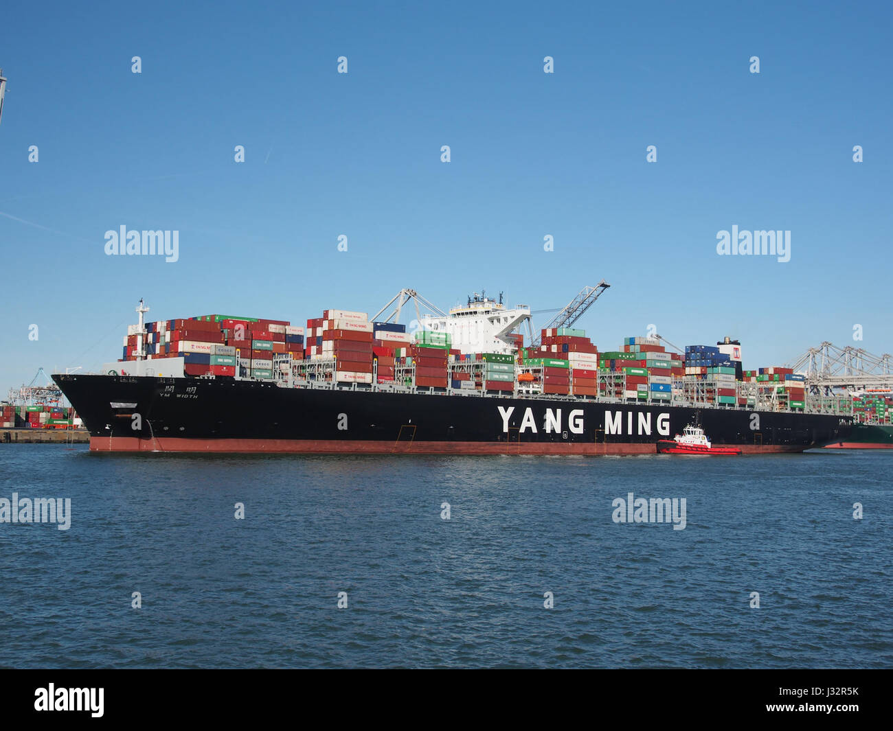 The YM Width, a large container ship with IMO number 9708447, arrives at the Port of Rotterdam in 2016. This ship is a significant part of global maritime shipping, transporting goods internationally. Stock Photo
