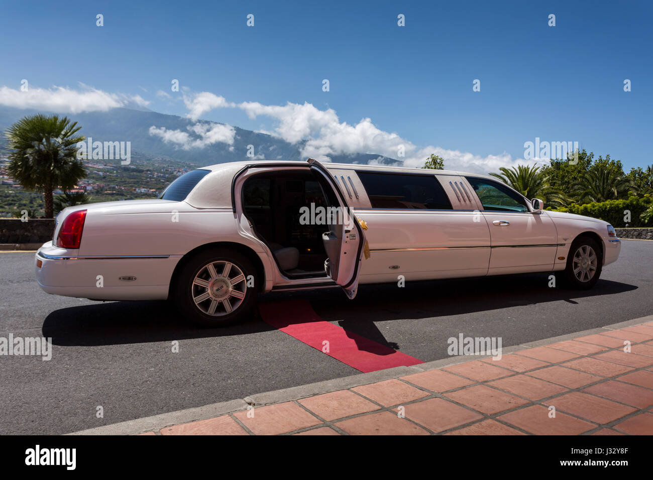 White Lincoln limousine car decorated for a wedding party and with red carpet leading to open door. Stock Photo