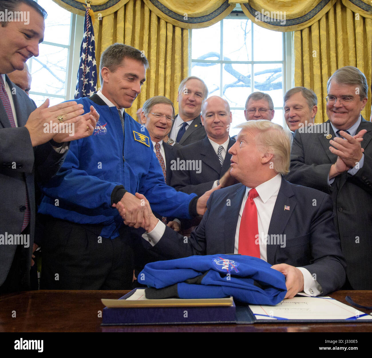 President Donald Trump, seated, shakes hands with NASA Astronaut Office Chief Chris Cassidy, after signing the NASA Transition Authorization Act of 2017, alongside members of the Senate, Congress, and National Aeronautics and Space Administration in the Oval Office of the White House in Washington, Tuesday, March 21, 2017.  Also pictured, from left, Sen. Ted Cruz, R-Texas, NASA Astronaut Office Chief Chris Cassidy, Rep. Lamar Smith, R-Texas, Sen. Luther Strange, R-AL, Rep. Robert Aderholt, R-AL, Rep. Frank Lucas, R-OK, Rep. Brian Babin, R-Texas, and Rep. John Culberson, R-Texas. Photo Credit:  Stock Photo
