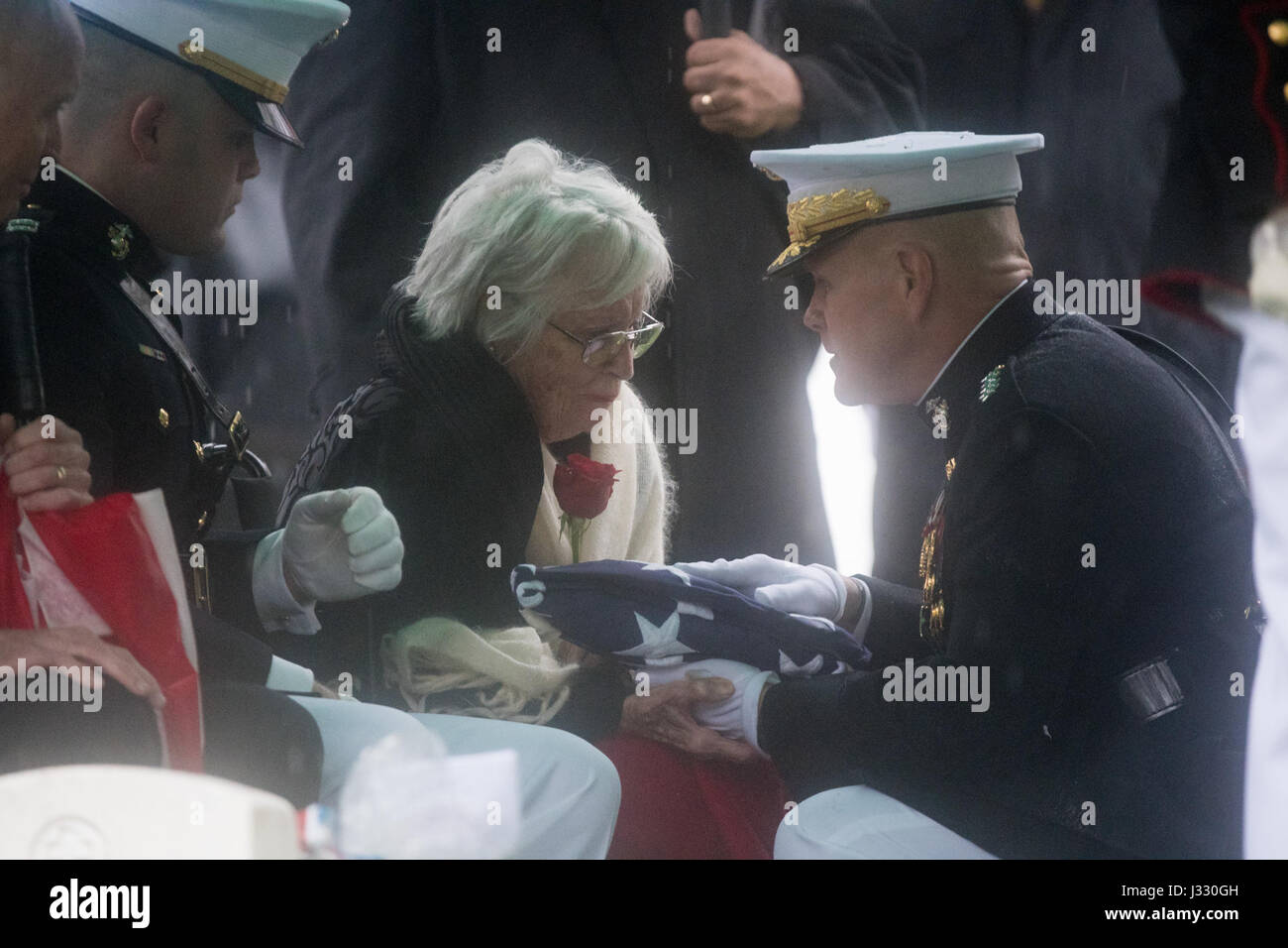 Annie Glenn, wife of former astronaut and U.S. Senator John Glenn receives the folded American flag from Commandant of the U.S. Marine Corps, General Robert B. Neller, during a graveside interment ceremony at Arlington National Cemetery in Virginia on Thursday, April 6, 2017, the day on which Glenn and Annie were married in 1943. He was the first American to orbit Earth on Feb. 20, 1962, in a five-hour flight aboard the Friendship 7 spacecraft. In 1998, Glenn broke another record by returning to space at the age of 77 on the Space Shuttle Discovery. Photo Credit: (NASA/Aubrey Gemignani) Stock Photo