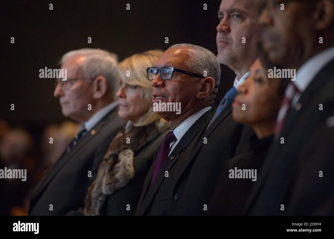 NASA Administrator Charles Bolden, 3rd from left, sings along with the choir, as he and Director of the Smithsonian's National Air and Space Museum Gen. J.R. &quot;Jack&quot; Dailey, left, and Apollo 11 astronaut Neil Armstrong's window Carol Armstrong, joined family, friends, and dignitaries to celebrate the life of former astronaut and U.S. Senator John Glenn, Saturday, Dec. 17, 2016 at The Ohio State University, Mershon Auditorium in Columbus. Photo Credit: (NASA/Bill Ingalls) Stock Photo