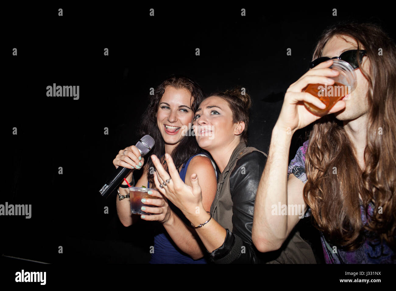 Friends doing karaoke at a nightclub Stock Photo
