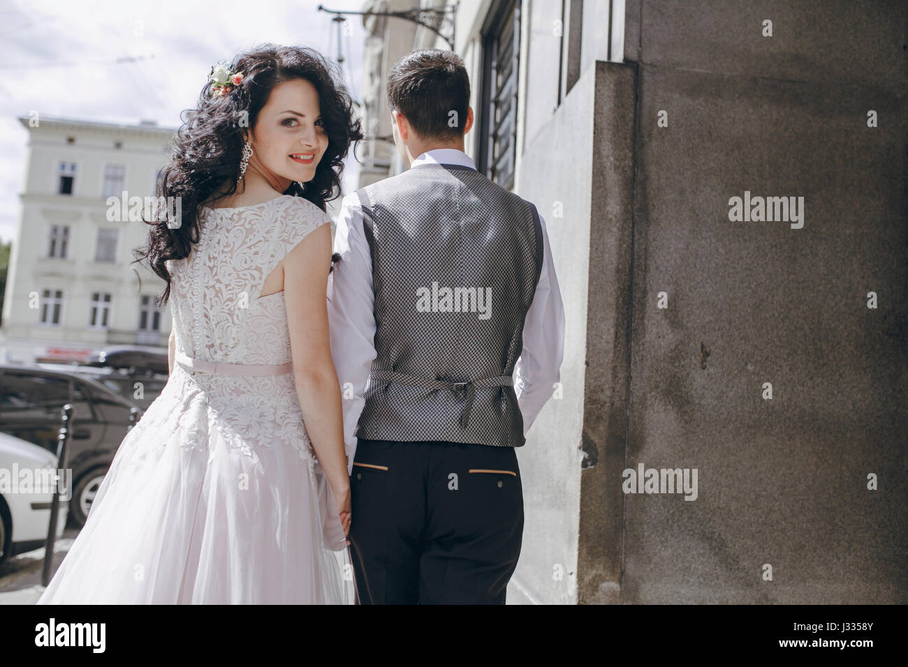 bride and groom walking in a sunny city at large buildings Stock Photo ...