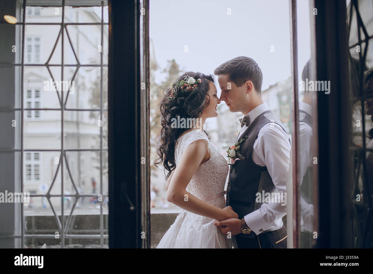 bride and groom standing by the window and kissing Stock Photo - Alamy