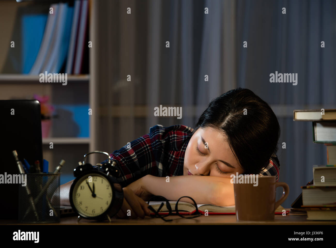 Tired students studying late at night, they are sleeping on the desktop and leaning on piles of books. mixed race asian chinese model. Stock Photo