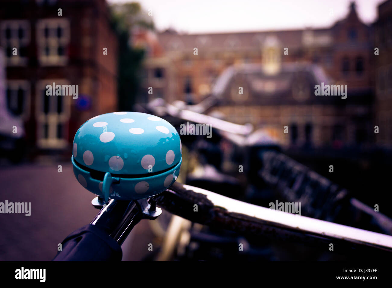 Polka dotted blue bike bell with old Amsterdam buildings in the background Stock Photo