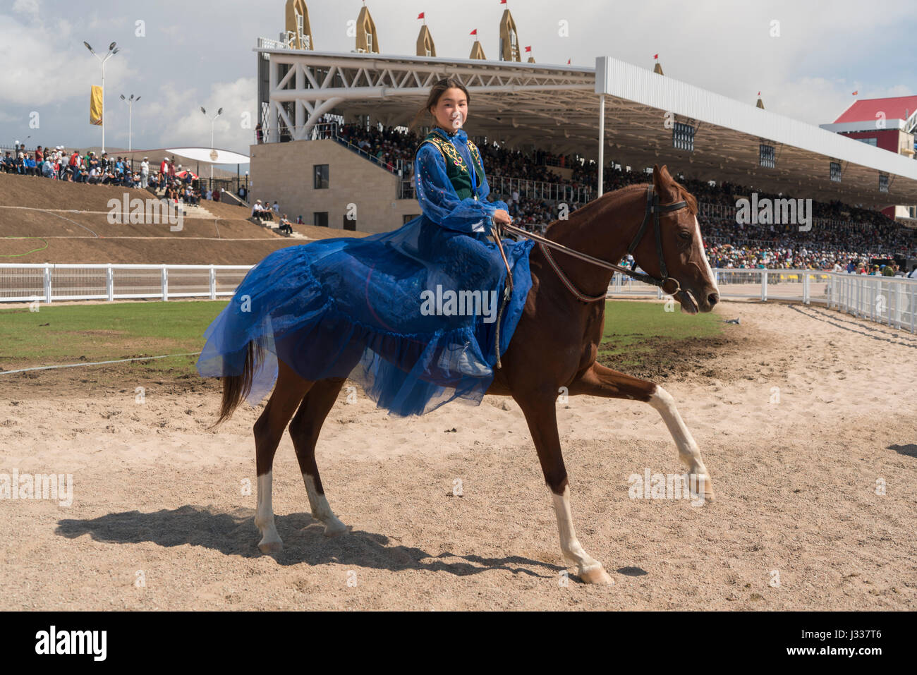 A Kyrgyz girl dressed in blue on a race horse at an horseracing event at the World Nomad Games 2016 in Cholpon Ata, Kyrgyzstan Stock Photo