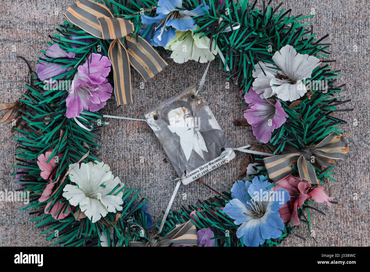 Wreath with a photograph of Soviet soldier Pyotr Atamas fallen during the Hungarian Uprising (1956) on his grave on the Soviet War Memorial at the Kerepesi Cemetery in Budapest, Hungary. Soviet soldier Pyotr Atamas was born on July 4, 1935 in Blagodatnoe (now in Stavropol Krai, Russia), and died in Budapest at age 21 on November 9, 1956. His grave on the Kerepesi Cemetery was unmarked until the last restoration works conducted in 2013-2015. Stock Photo