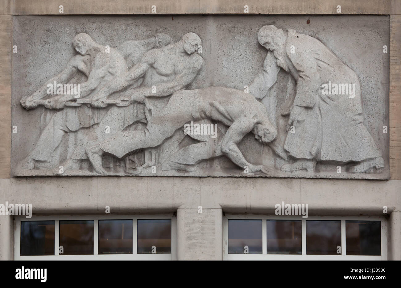 Workers rescue the injured person. Relief by Hungarian sculptor Mihaly Biro on the south wing of the Art Nouveau building of the Budapest Workers Insurance Fund in Budapest, Hungary. The building, now used as the seat of the National Social Insurance Centre (OTI), was designed by Hungarian architects Marcell Komor and Dezso Jakab and built in 1913. The north wing was added in the 1930s. Stock Photo