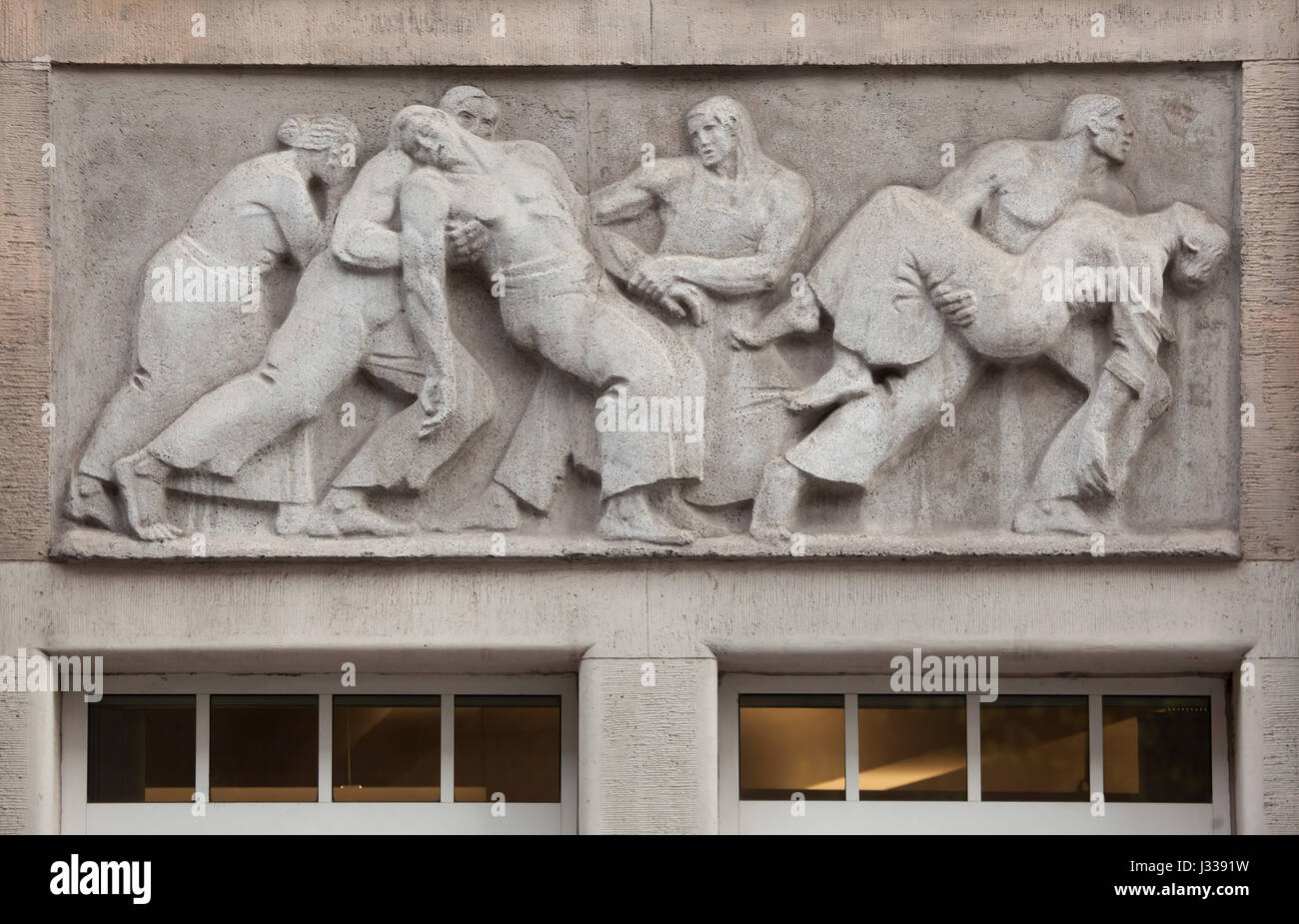 Rescuing of the injured workers. Relief by Hungarian sculptor Mihaly Biro on the south wing of the Art Nouveau building of the Budapest Workers Insurance Fund in Budapest, Hungary. The building, now used as the seat of the National Social Insurance Centre (OTI), was designed by Hungarian architects Marcell Komor and Dezso Jakab and built in 1913. The north wing was added in the 1930s. Stock Photo