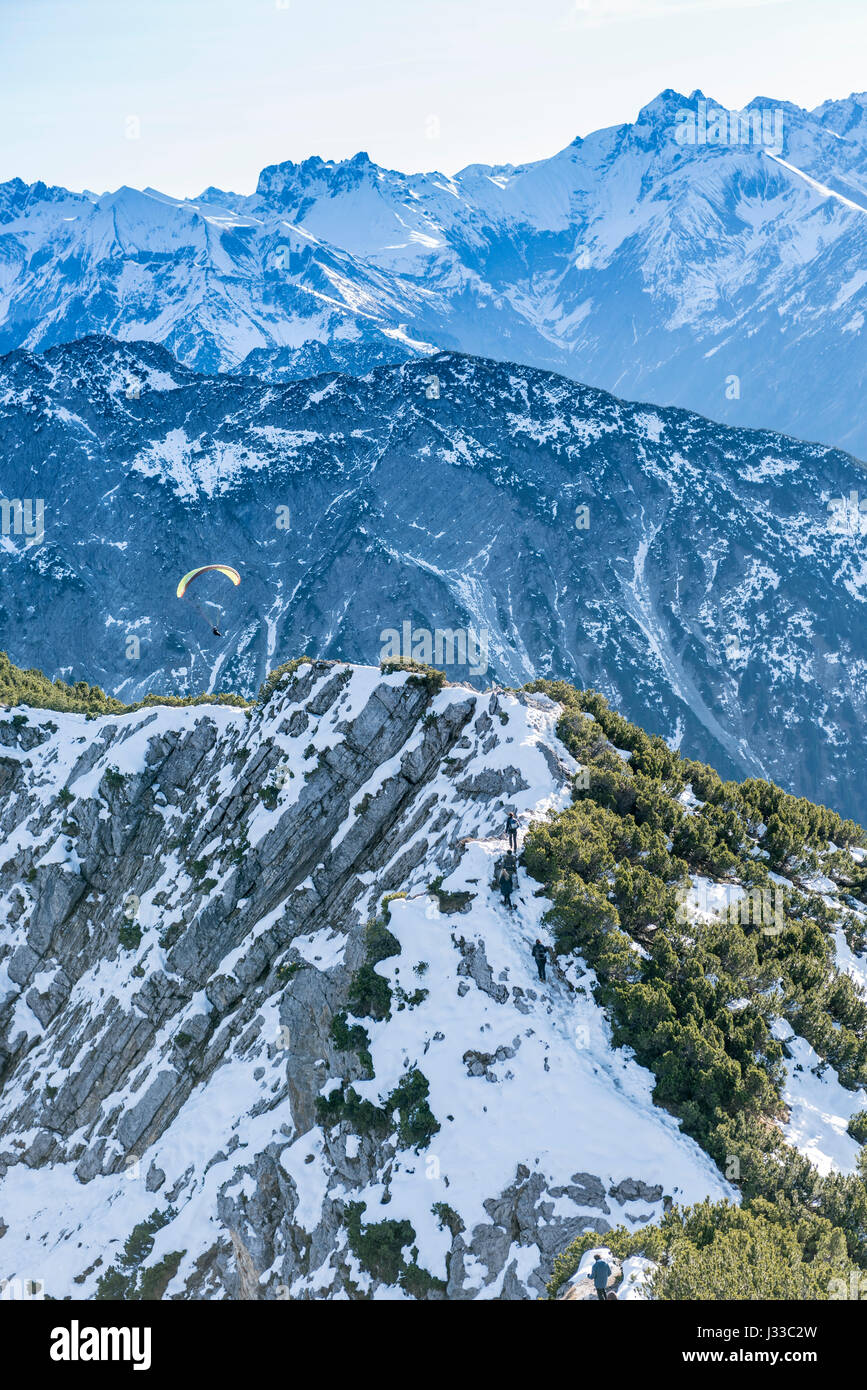 View from the top of Rubihorn cross to snowy trail in the direction Nebelhorn with paragliders in the sky, Oberstdorf, Allgaeu, Germany Stock Photo