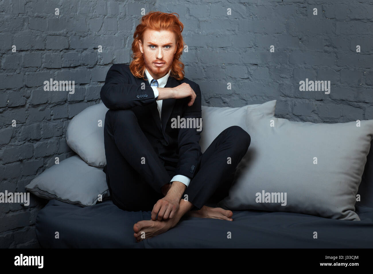 The guy with the red hair and beard, sitting on the sofa. Freckles on his face. Stock Photo