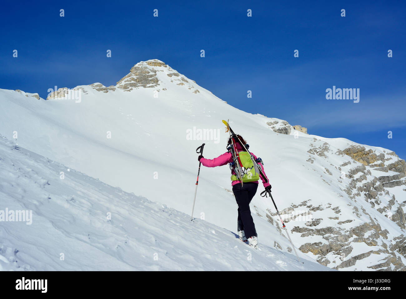 Female back-country skier ascending to Birkkarspitze, Oedkarspitze in backgrounds, Karwendel range, Tyrol, Austria Stock Photo