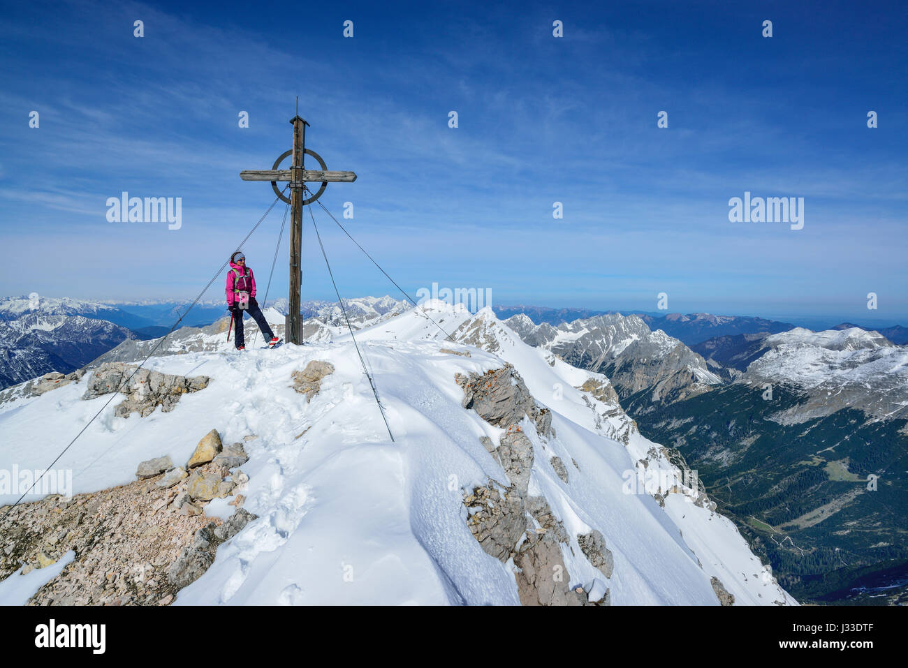 Woman standing beside summit cross of Birkkarspitze, Karwendel range, Tyrol, Austria Stock Photo