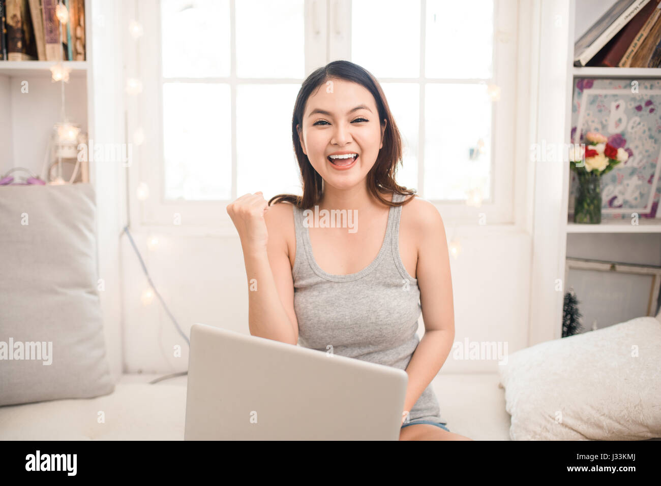 Happy excited asian young woman working on a laptop at home Stock Photo ...