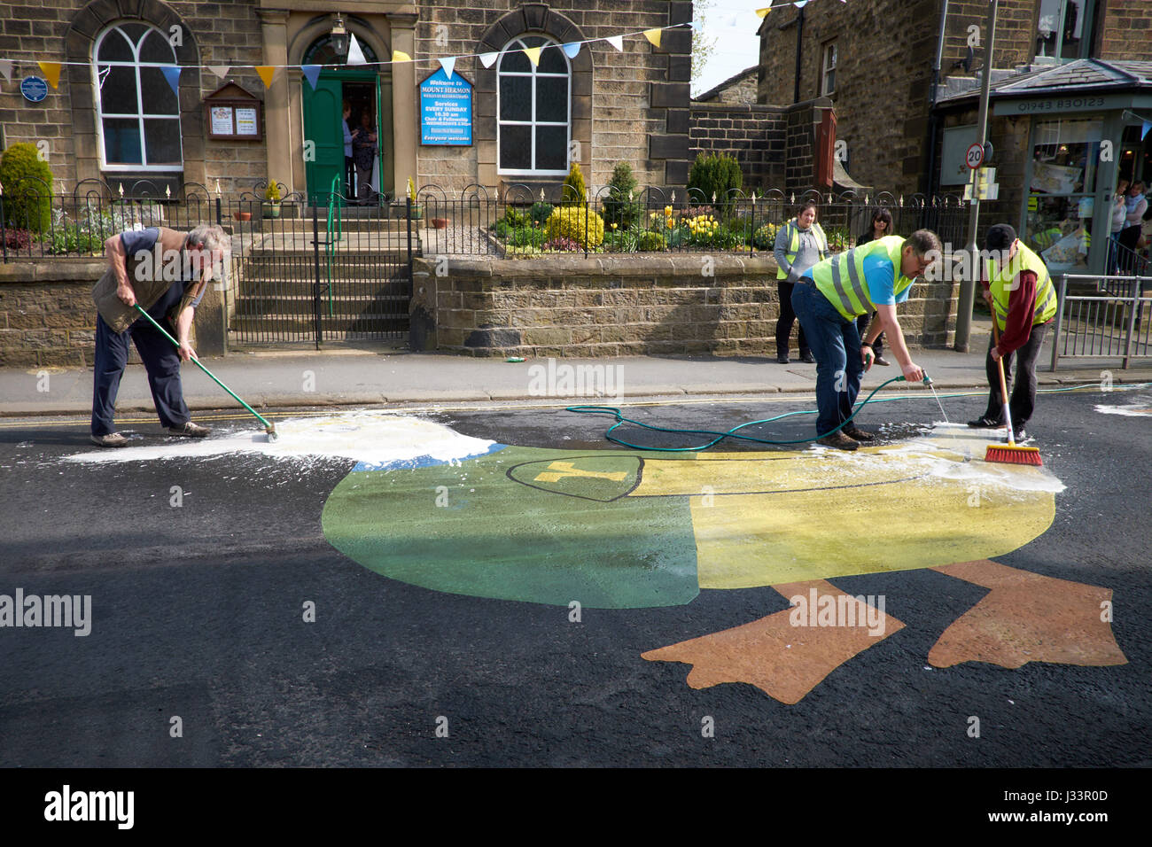 Three people clean a large printed duck on the road on Addingham