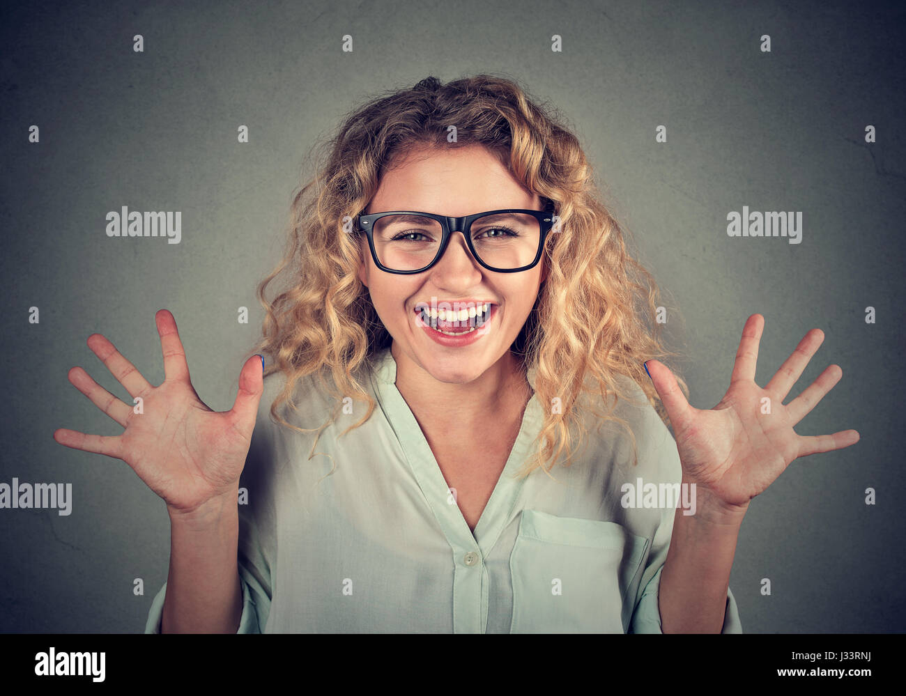 super excited funky looking girl in glasses screaming isolated on gray wall background Stock Photo