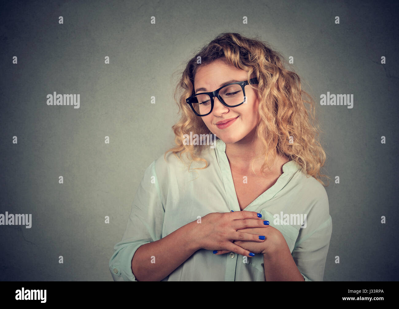 Lack of confidence. Shy young woman feels awkward isolated on grey wall background. Human emotion body language life perception Stock Photo