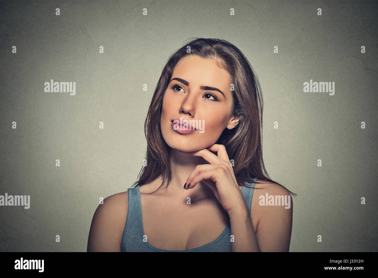 Portrait happy beautiful woman thinking looking up isolated grey wall ...
