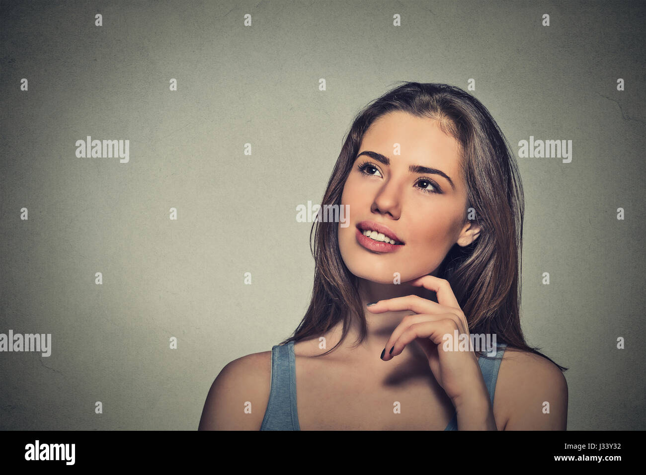 Portrait happy beautiful woman thinking looking up isolated grey wall ...