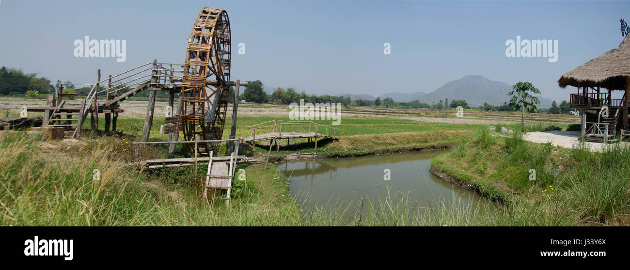 Thai Dam Cultural Village and big wooden turbine baler water wheel or wood noria water with landscape rice field mountain in Chiang Khan at Loei, Thai Stock Photo