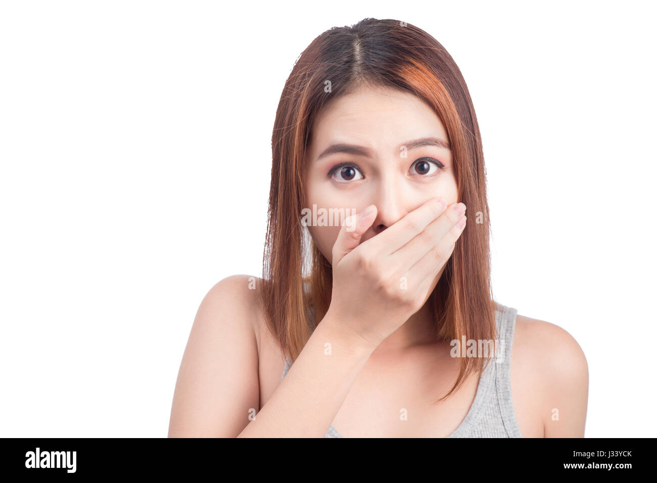 Young adult asian woman holding hand over her mouth over white background Stock Photo