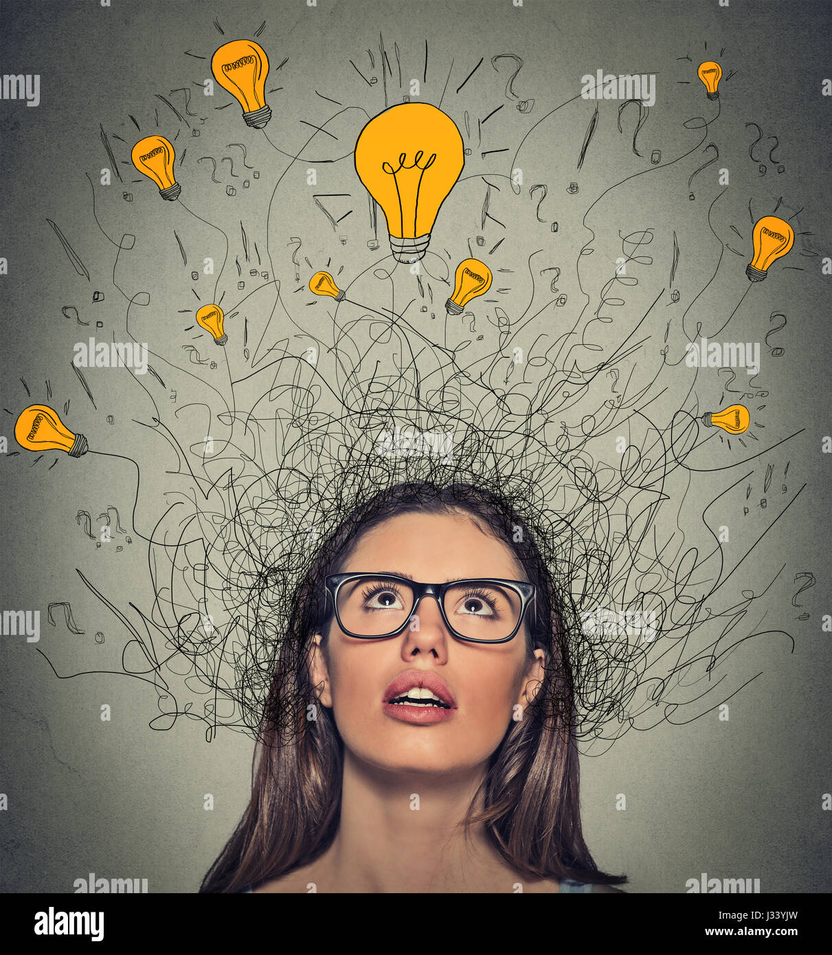 Closeup thinking woman with question signs and light idea bulb above head looking up on gray wall background Stock Photo