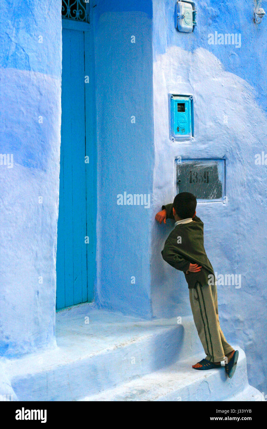 A boy plays hide and seek inside the old medina of Chefchouen. Rif mountains, Morocco. Stock Photo