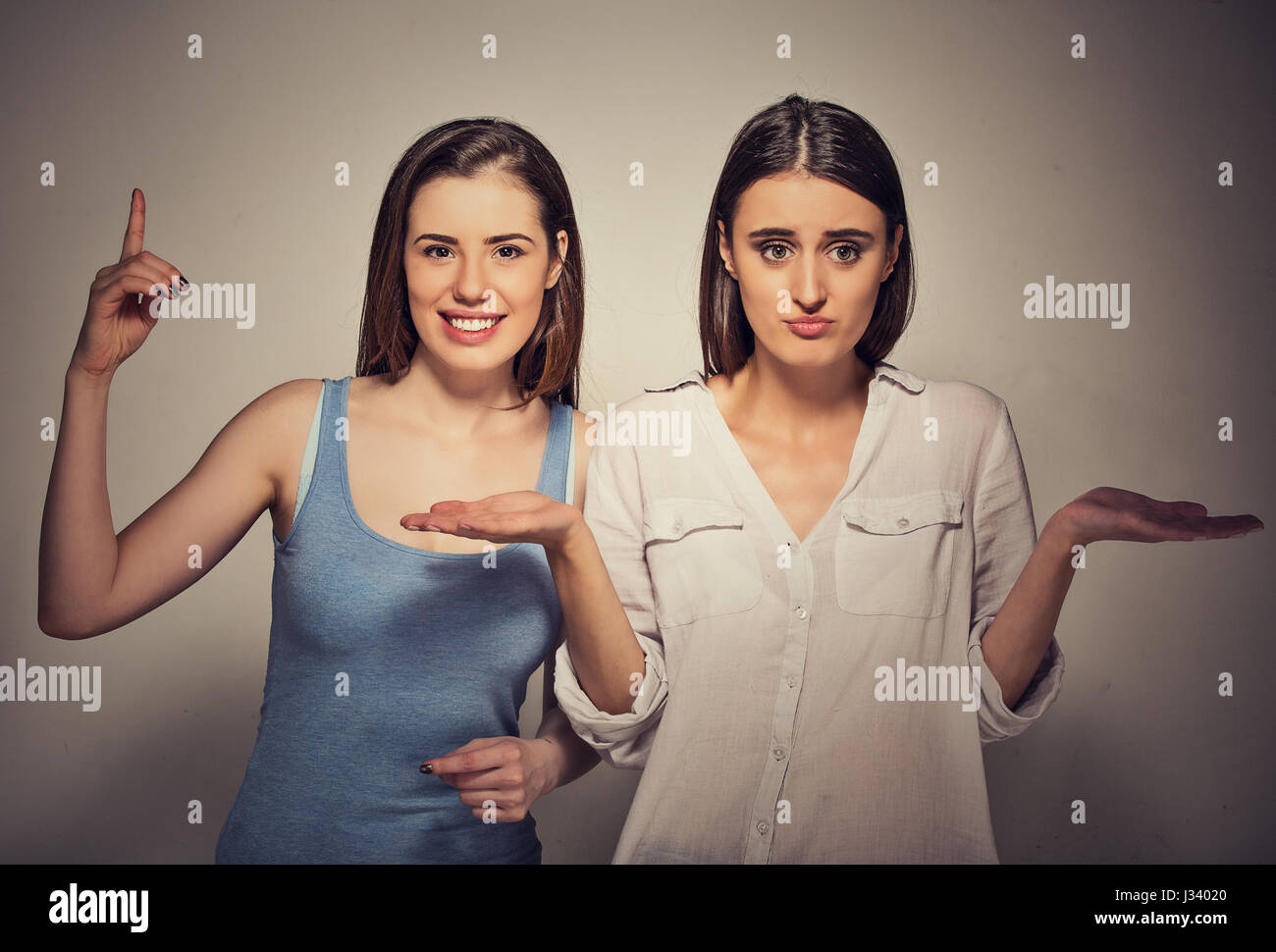 Closeup portrait excited, optimistic woman having solution, and bored, annoyed clueless girl isolated on gray background. Human emotions, expressions, Stock Photo