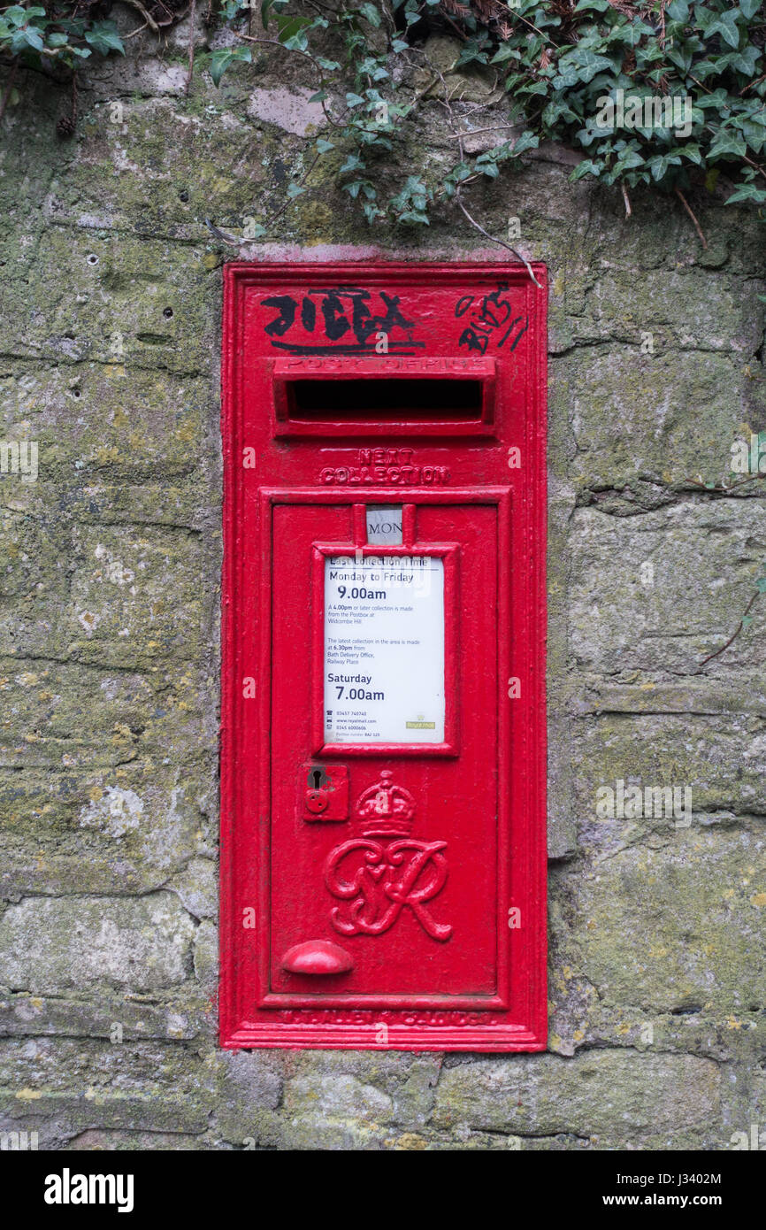 a view of black graffiti on a pill post letter box in a stone wall Stock Photo