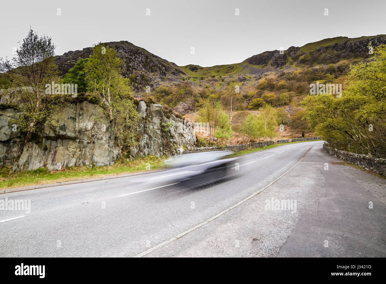 A speeding car rushes past imposing landscape Stock Photo