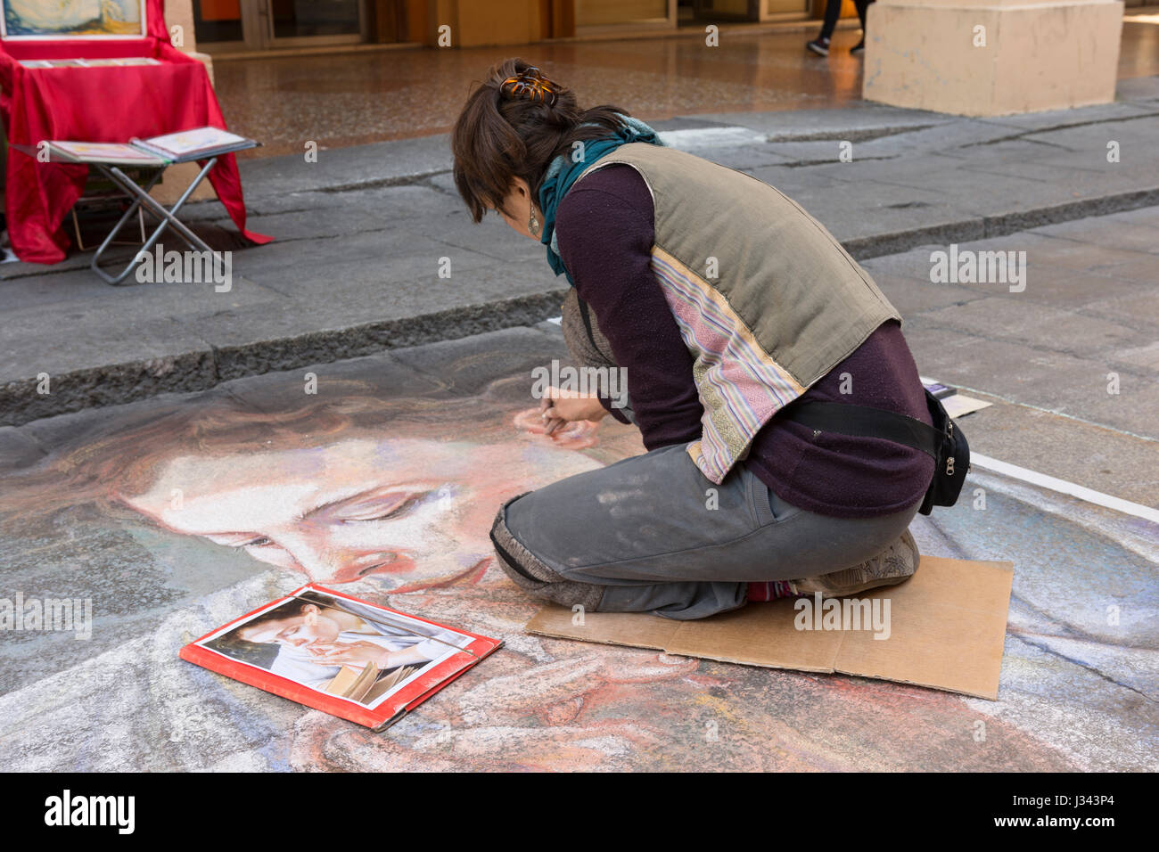 a young street artist while drawing with chalk on the pavement Stock Photo