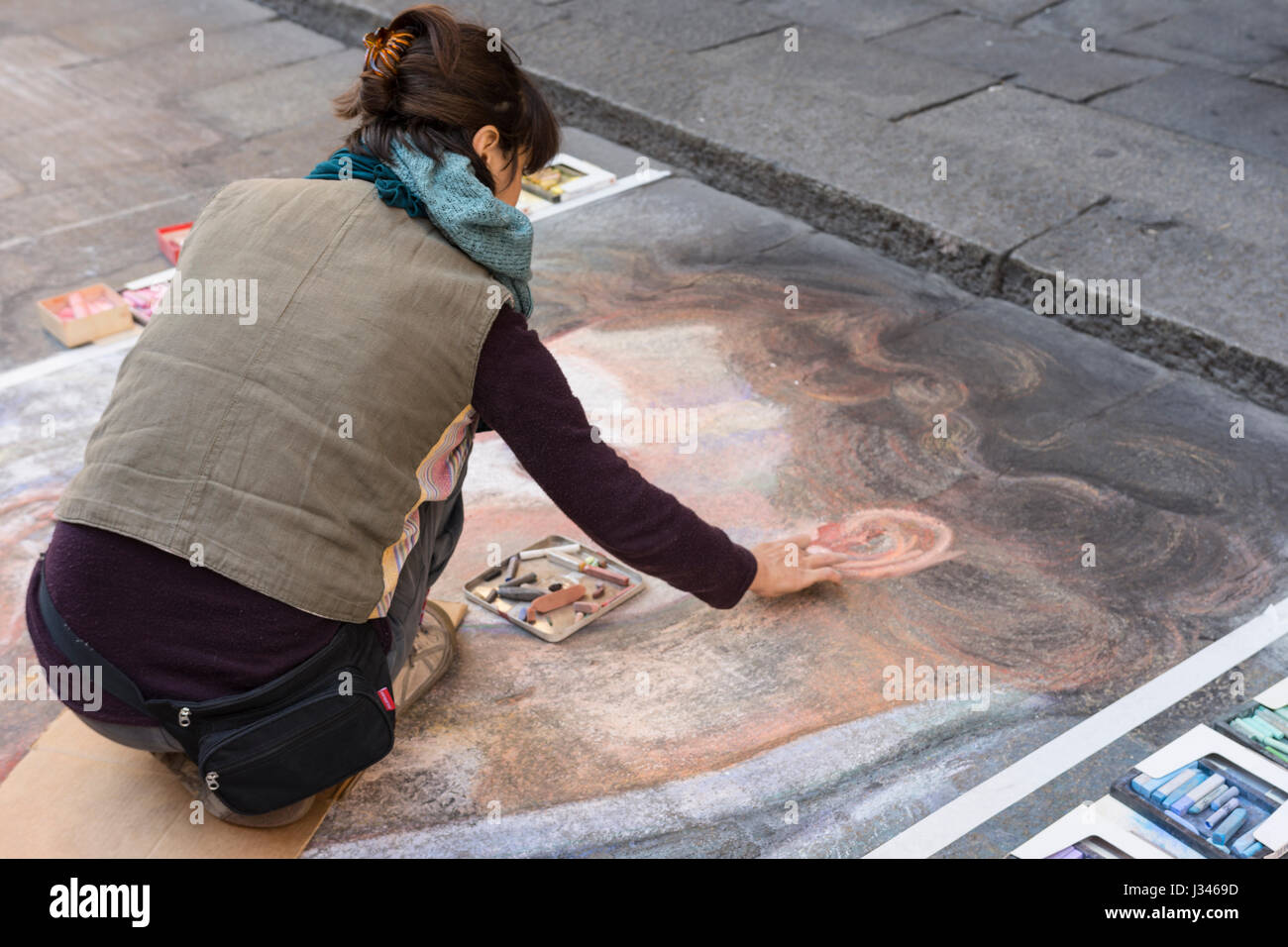 a young street artist while drawing with chalk on the pavement Stock Photo
