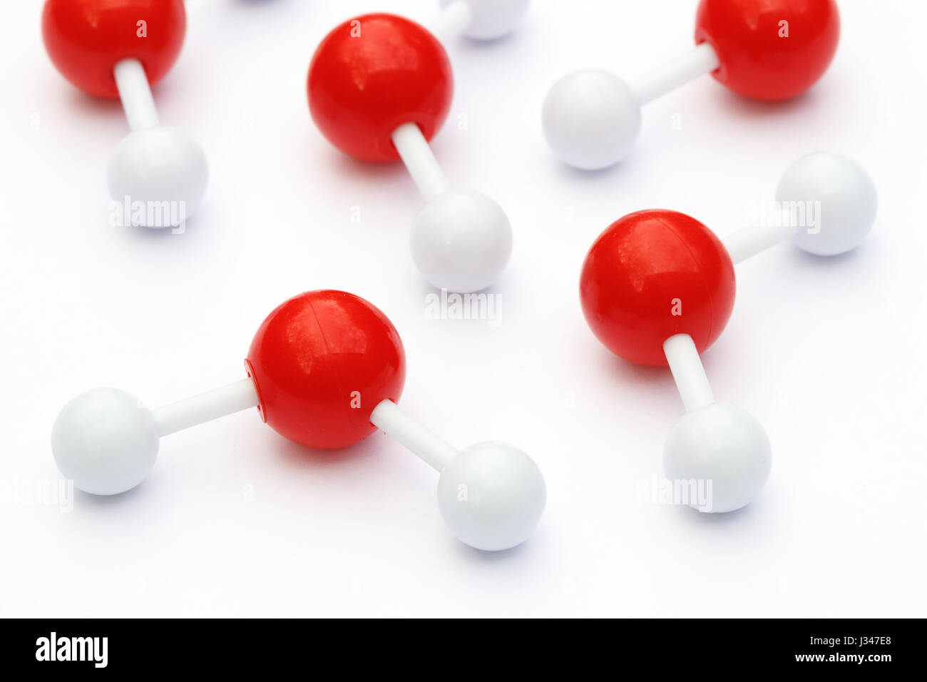 Plastic ball-and-stick models of water molecules on a white background. Water molecules consist of two hydrogen atoms connected to an oxygen atom. Stock Photo