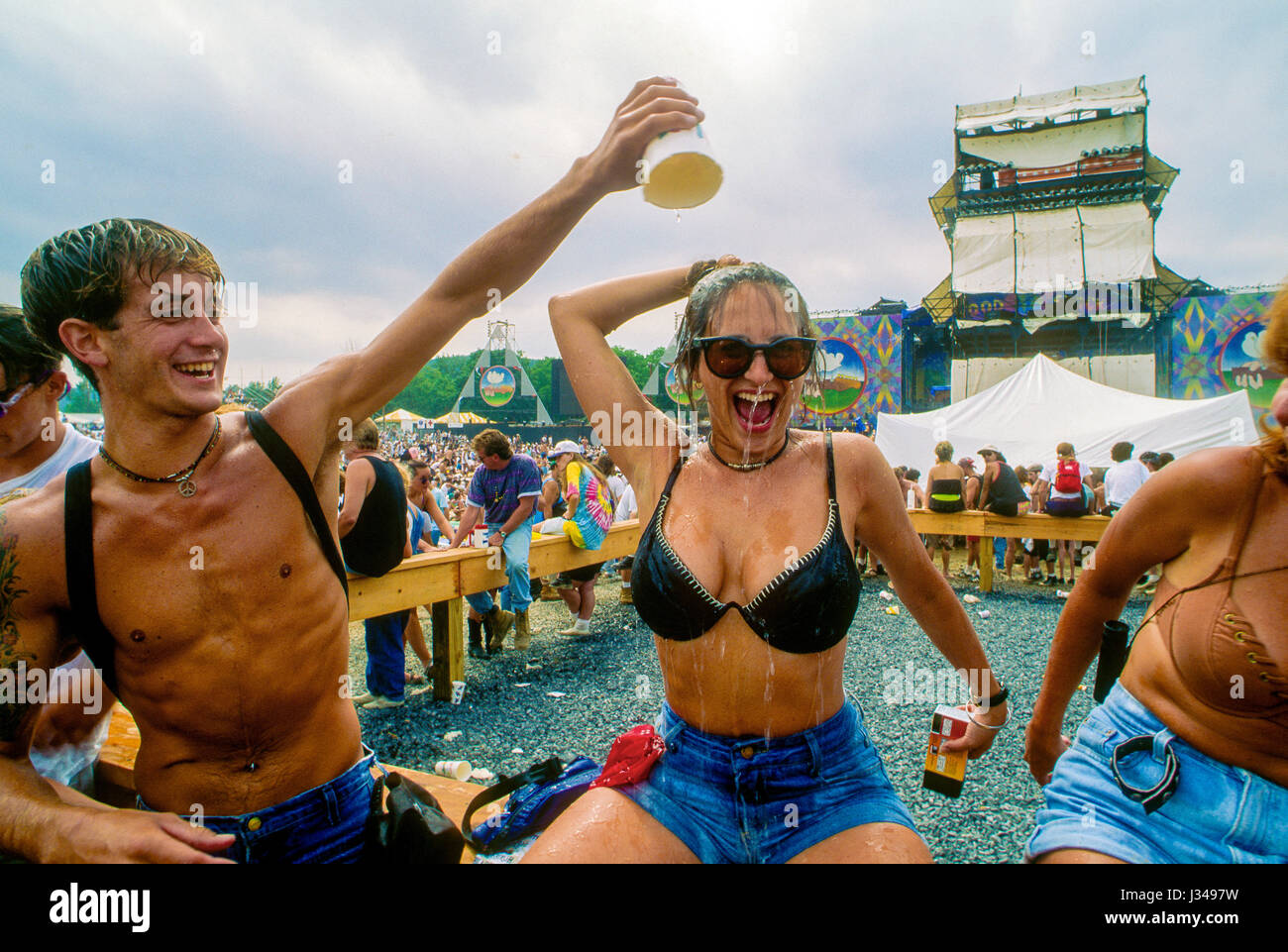 Woman concert goer gets a cup of water poured over her head in an effort to keep cool while attending the 25th anniversary of the orginal Woodstock music festival which took place on the WInston Farm in Saugerties New York, August 12, 1994.  Photo by Mark Reinstein Stock Photo