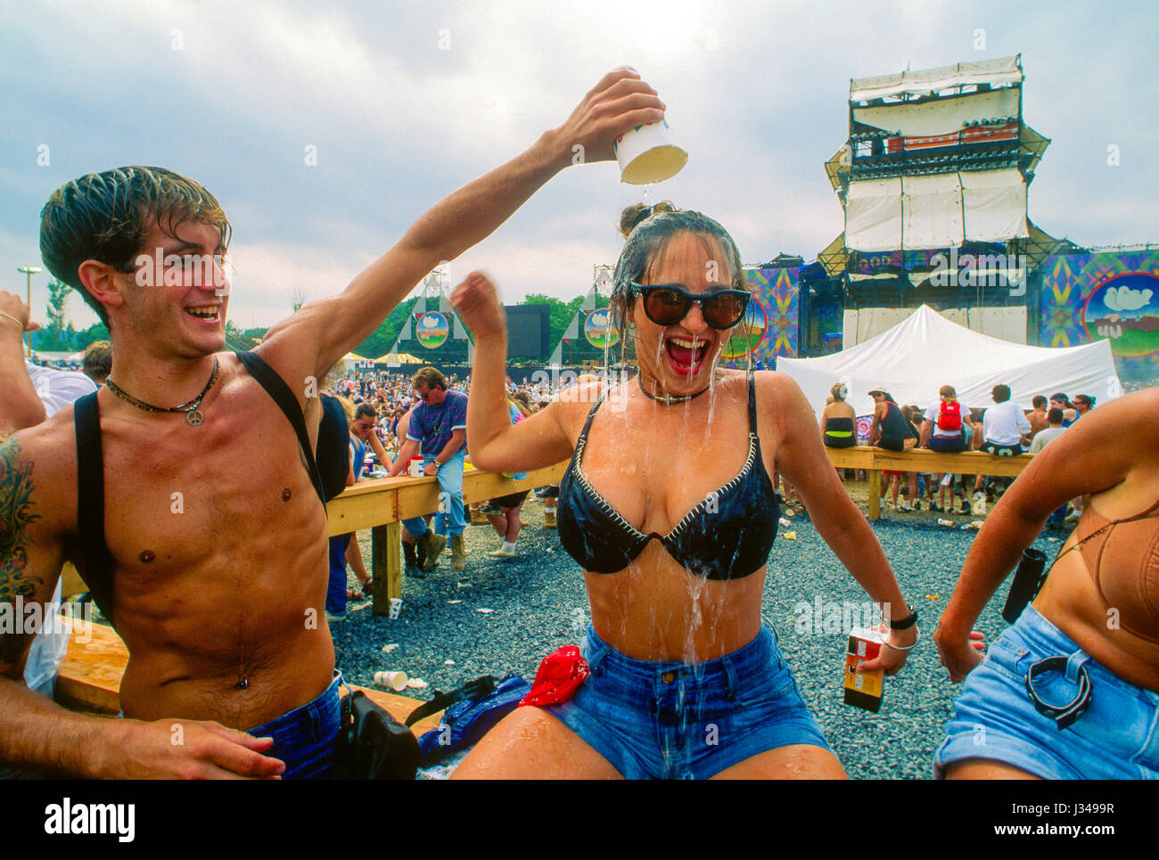 Woman concert goer gets a cup of water poured over her head in an effort to keep cool while attending the 25th anniversary of the orginal Woodstock music festival which took place on the WInston Farm in Saugerties New York, August 12, 1994.  Photo by Mark Reinstein Stock Photo